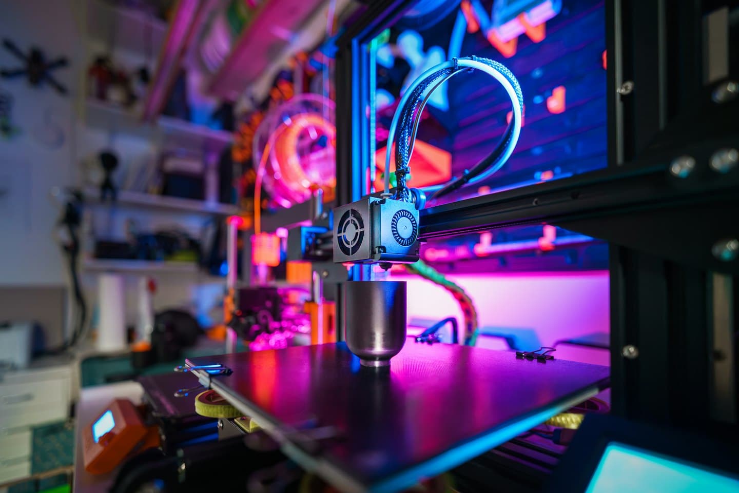 3D printer extruder head creating a metallic cup object.